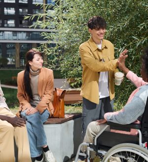 Group of young people greeting their friend with disability outdoors, they giving high-five to each other